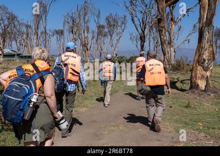 Lake Naivasha, Kenya - March 4, 2023: Group of tourists wearing life jackets head to the boats for a safari to Crescent Island Stock Photo