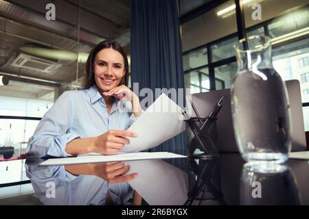 Happy young company manager posing for camera at work in office Stock Photo