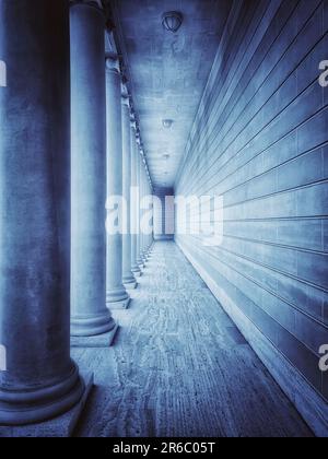 Long and narrow hallway with tall columns and concrete wall. Stock Photo