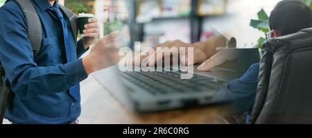 Remote and hybrid work concept. A man uses his smartphone and computer notebook to work or do his jobs from different spaces rather than from an offic Stock Photo