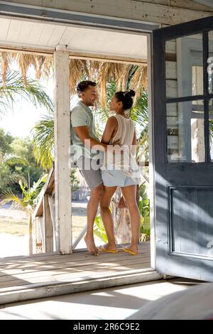 Romantic caucasisn young couple looking at each other while standing in balcony seen through doorway. Unaltered, love, together, vacation, tourist res Stock Photo