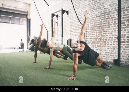 Building strength from side to side. a fitness group doing the side plank together at the gym. Stock Photo