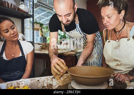 Making something beautiful takes a bit more time. a group of young people working with clay in a pottery studio. Stock Photo