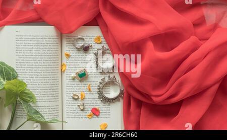 A selection of jewelry pieces is laid out on an open book, with the pages spread wide Stock Photo