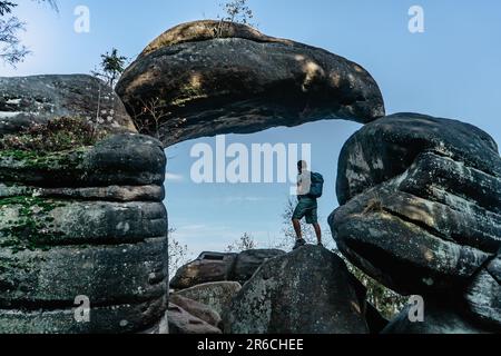 Man backpacker in Rock Gate in nature reserve Broumov Walls, Czech Republic.Old sandstone rock formation in Broumovske steny.Active male traveler Stock Photo