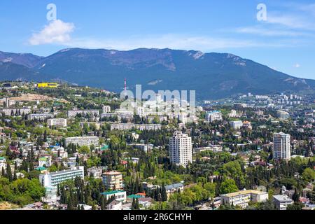 city in the mountains. Tall houses surrounded by cypress trees against the backdrop of mountains. Stock Photo