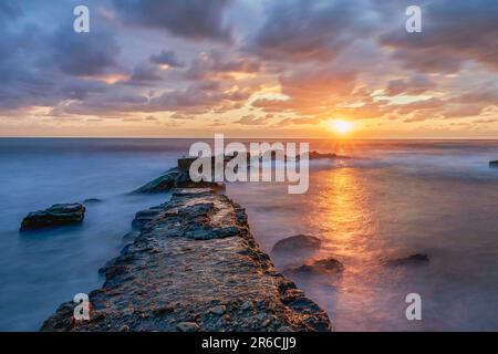 Sunrise on urbanova beach (agua amarga) between rocks. In urbanova, province of Alicante, Spain. Stock Photo