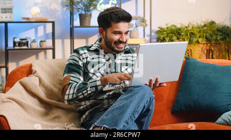 Oh my God Wow. Surprised indian man using laptop computer, receive good news message, shocked by sudden victory, celebrate lottery jackpot win purchases online shopping at home. Lifestyle technologies Stock Photo