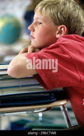 Bored student leaning on a stack of books Stock Photo - Alamy