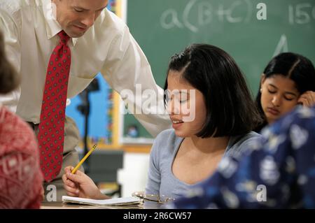 pupil being helped by her teacher in a middle school classroom Stock Photo