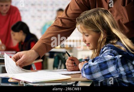 pupil being helped by her teacher in a middle school classroom Stock Photo