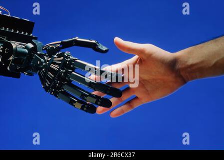 A human shakes hands with a robot Stock Photo
