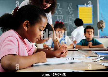African-American Elementary school student working in a notebook at her desk Stock Photo