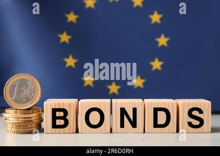 Word Bonds made of wooden cubes with letters and stacked coins against European union flag Stock Photo