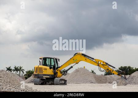 Yellow excavator with extended bucket at a landfill in South Florida USA. Stock Photo