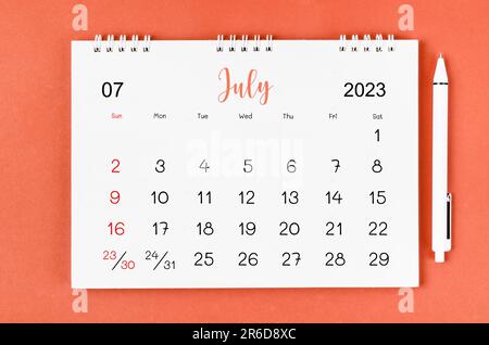 July 2023 Monthly desk calendar for 2023 year and pen on red background. Stock Photo