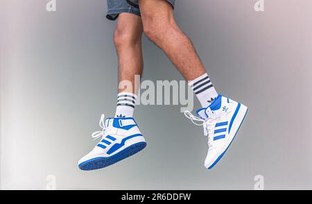 A young man jumps up in Adidas Forum Mid white and blue sneakers on May 20, 2023 in Bangkok, Thailand. Stock Photo