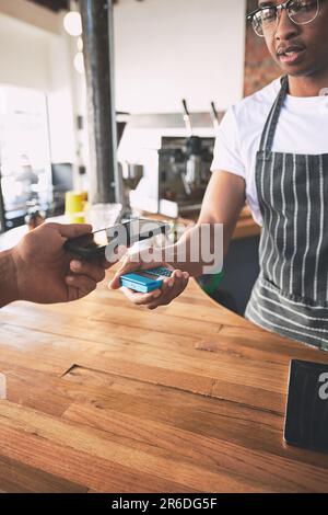 Tap and go for coffee on the go. a man using a smartphone to make a payment in a cafe. Stock Photo