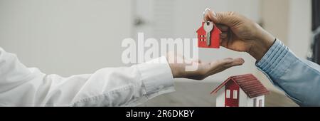 real estate agent holding house key to his client after signing contract, concept for business loan, investment mortgage, real estate, moving home or Stock Photo