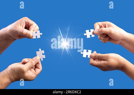 Hands holding jigsaw puzzles piece with clear blue background, success business, solution strategy, teamwork partnership concept Stock Photo