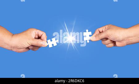 Hands holding jigsaw puzzles piece with clear blue background, success business, solution strategy, teamwork partnership concept Stock Photo