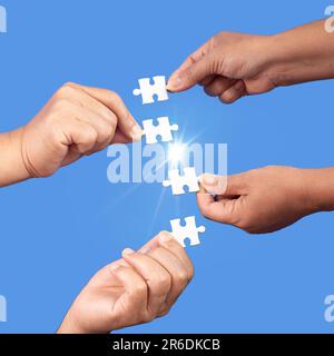 Hands holding jigsaw puzzles piece with clear blue background, success business, solution strategy, teamwork partnership concept Stock Photo
