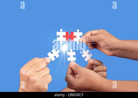 Hands holding jigsaw puzzles piece with clear blue background, success business, solution strategy, teamwork partnership concept Stock Photo