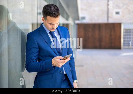 Handsome economist, lawyer, CEO, entrepreneur, executive director and businessman typing with smartphone outside the office. Stock Photo