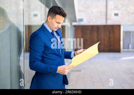 Handsome economist, lawyer, CEO, entrepreneur, executive director and businessman consulting financial documents outside the office. Stock Photo