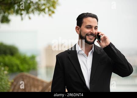 Portrait of handsome businessman outdoors at rooftop talking on mobile phone horizontal shot Stock Photo