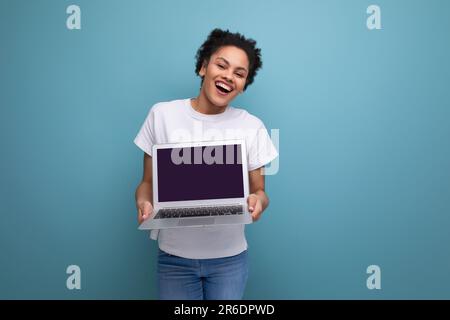 young happy brunette woman with afro hair in a white tank top holds a laptop for work in her hands. business concept Stock Photo