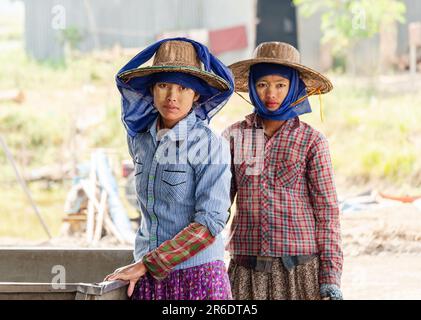 Two young female workers at a fish farm at the Irrawaddy Delta in Myanmar. Shallow depth of field with only the woman to the left in focus. Stock Photo