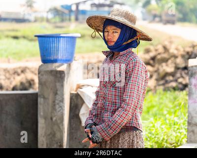 Young female worker at a fish farm at the Irrawaddy Delta in Myanmar. Shallow depth of field with only the woman to the left in focus. Stock Photo