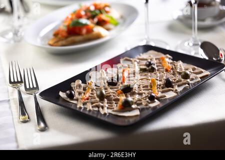 Italian appetizer with veal slices, tuna salsa and olives served in an Italian restaurant. Stock Photo