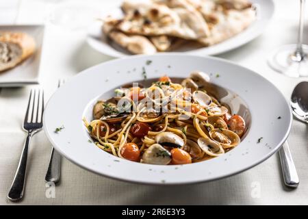 Plate full of spaghetti alle vongole e pomodorini served on a restaurant table. Stock Photo