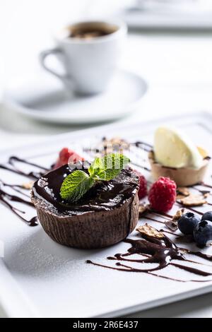 Brownies with ice cream and fruit, mint and chocolate decoration with an espresso on a cafe table. Stock Photo