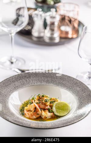 Grilled shrimps on a melted butter with garlic, herbs and chilli with a slice of lime. Stock Photo