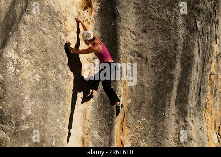 A young woman rock climbs on a streaked wall of limestone, Castle Hill, New Zealand. Stock Photo