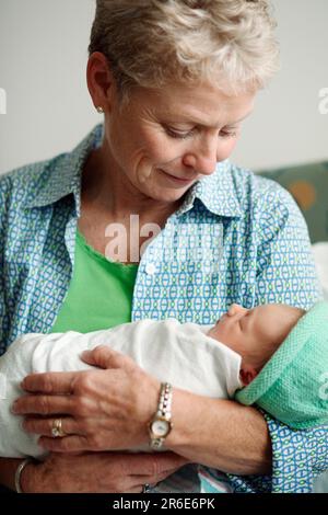 A woman holds a newborn baby girl the day after she was born. Stock Photo