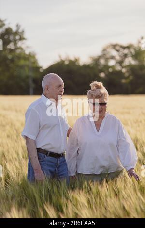happy elderly people in wheat field walking in nature, elderly couple Stock Photo