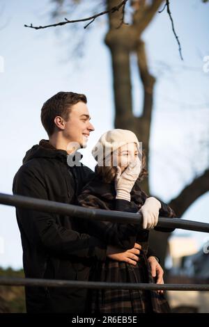 woman in coat and beret hugs man on streets of Paris in autumn Stock Photo