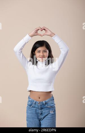 A smiling young woman stands confidently with her hands resting behind her head, showcasing her beauty and poise Stock Photo