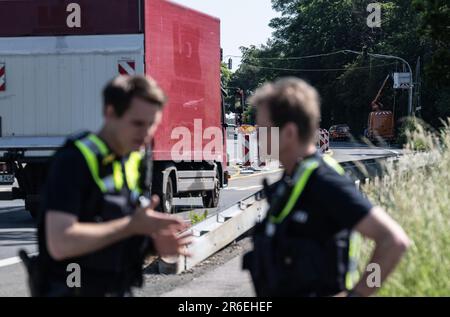 09 June 2023, North Rhine-Westphalia, Lüdenscheid: Two police officers observe traffic at the Lüdenscheid exit. Around a month after the demolition of the A45 Rahmede viaduct in Lüdenscheid, the city wants to impose a complete ban on trucks passing through the town after a year and a half of inconvenient detour traffic. The police plan to carry out extensive checks from June 12. Photo: Bernd Thissen/dpa Stock Photo
