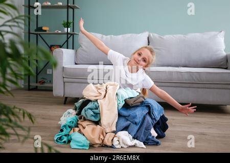 Pile of carelessly scattered clothes on floor.The child puts things in order in the room. Stock Photo