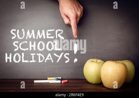 Summer school holidays. Pieces of chalk and apples on the teacher's desk. Stock Photo