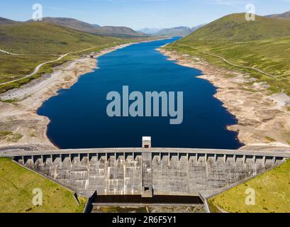 Garve, Scotland, UK. 9th June 2023. An aerial view of Glascarnoch Dam south of Ullapool. Prolonged drought conditions in the Scottish Highlands have led to low water levels in Glascarnoch reservoir near Garve.  Authorities have warned of possible water restrictions if the dry weather continues. Iain Masterton/Alamy Live News Stock Photo