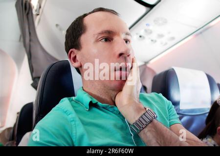 Young Man Having Anxiety Attack In Airplane Stock Photo