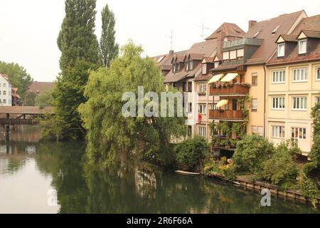 A tranquil scene of a small town with a riverfront view of the empty river, revealing a row of buildings in the background Stock Photo