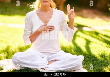 Beautiful mature woman meditating in green sunny garden, healthy lifestyle Stock Photo