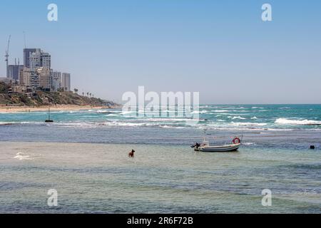 small beached Fishing boat. Photographed in Jaffa, Israel. Bat Yam in the Background Stock Photo